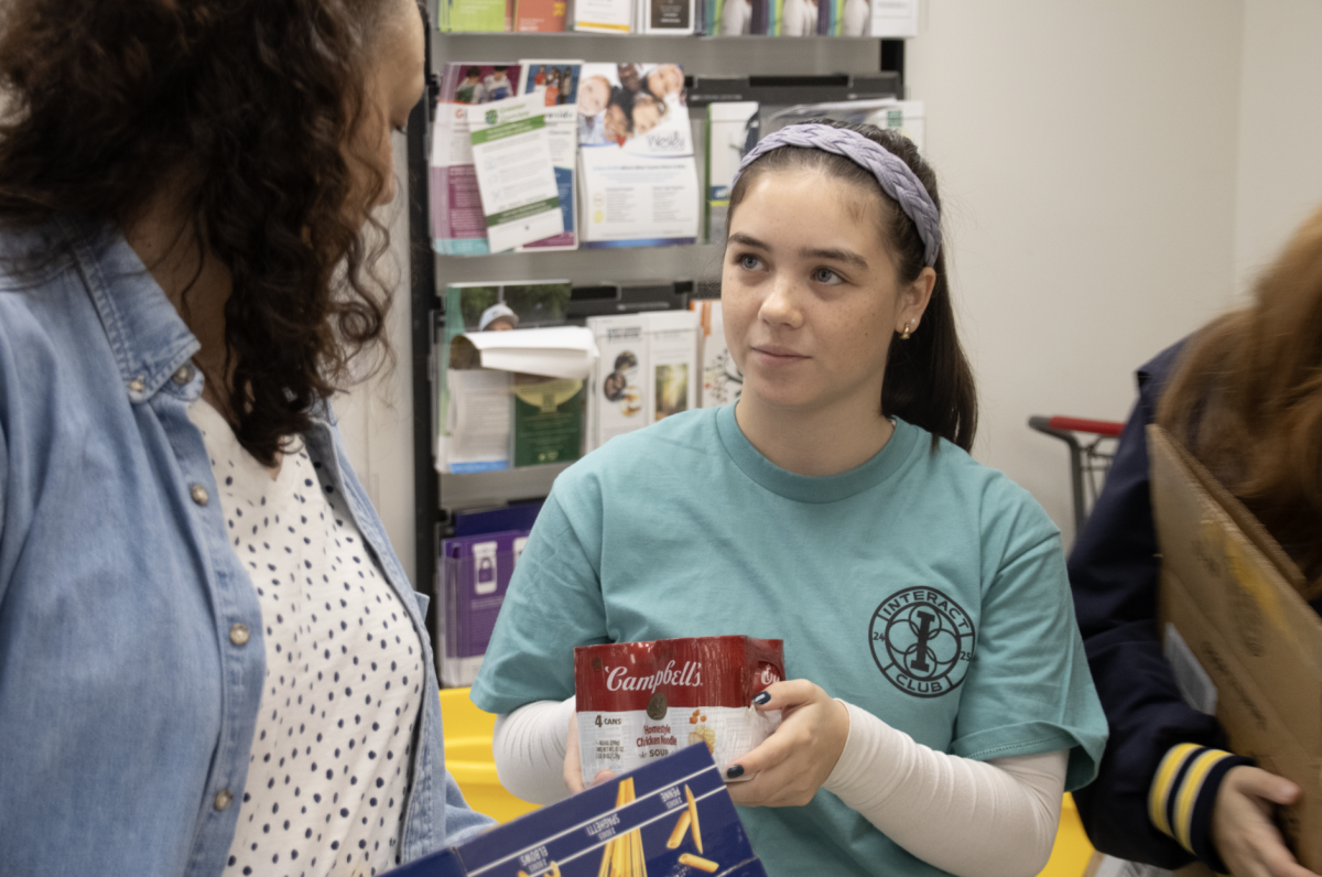 STACKING UP:  Junior Kendall Marquardt helps pack boxes filled with donated good into a pile, where they will be carried into the pantry by other volunteers. 